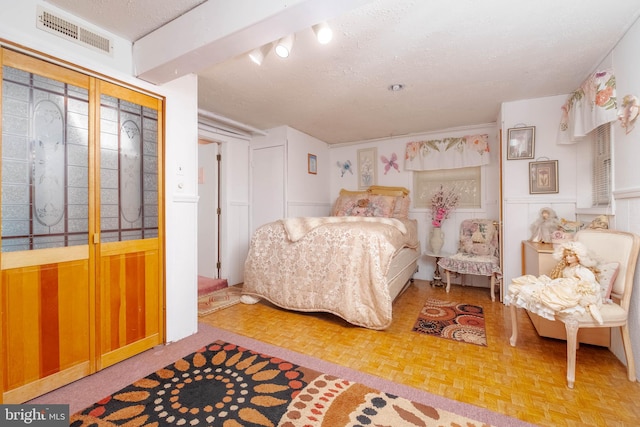 bedroom with parquet floors and a textured ceiling