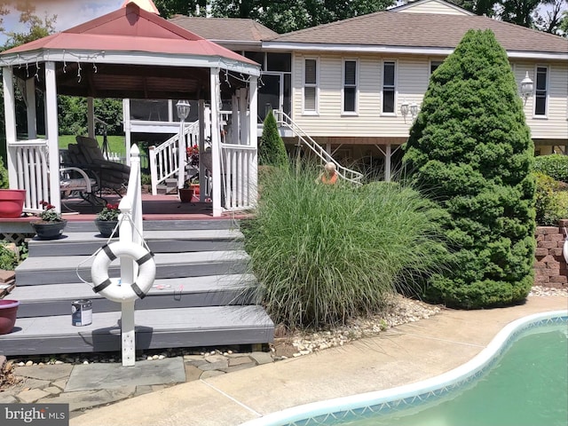 rear view of property with a swimming pool side deck and a gazebo