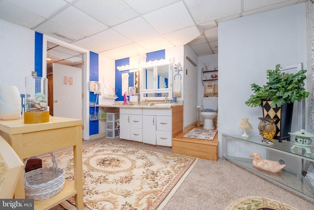 bathroom featuring toilet, vanity, and a drop ceiling