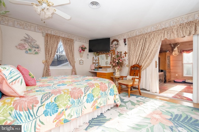 bedroom featuring light wood-type flooring, multiple windows, and ceiling fan