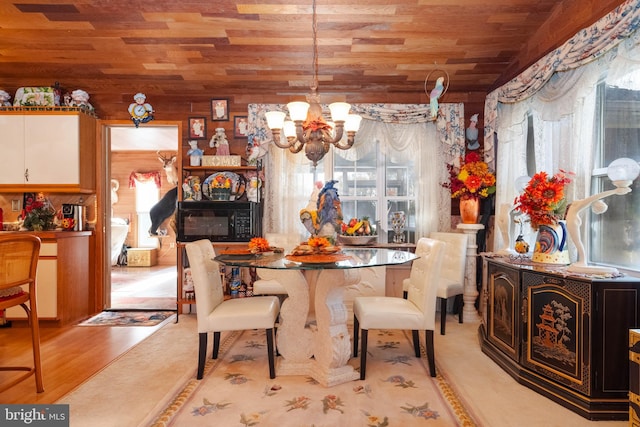 dining space featuring light hardwood / wood-style flooring, a notable chandelier, a healthy amount of sunlight, and wood ceiling