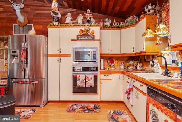 kitchen featuring sink, appliances with stainless steel finishes, vaulted ceiling, and white cabinets