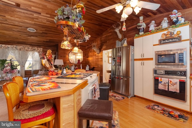 kitchen with stainless steel appliances, light hardwood / wood-style floors, vaulted ceiling, ceiling fan, and white cabinetry