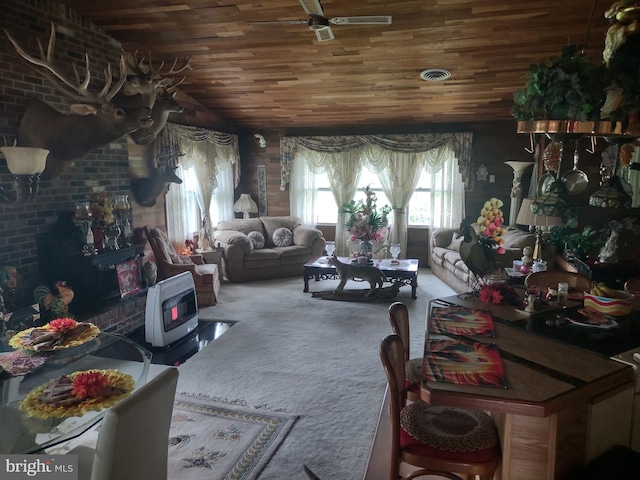 interior space with carpet flooring, vaulted ceiling, wood ceiling, a wood stove, and ceiling fan