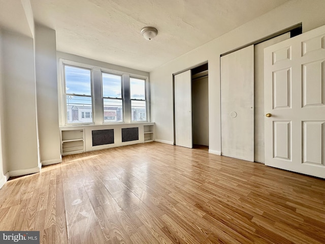 unfurnished bedroom with hardwood / wood-style floors and two closets