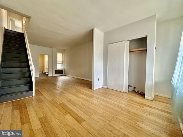 unfurnished living room with baseboard heating and light wood-type flooring