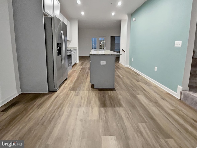 kitchen featuring white cabinets, a kitchen island with sink, light wood-type flooring, sink, and stainless steel appliances