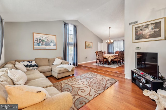 living room featuring light hardwood / wood-style flooring, a chandelier, and vaulted ceiling