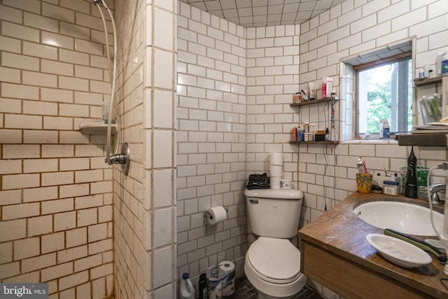 bathroom featuring toilet, walk in shower, vanity, and tile walls