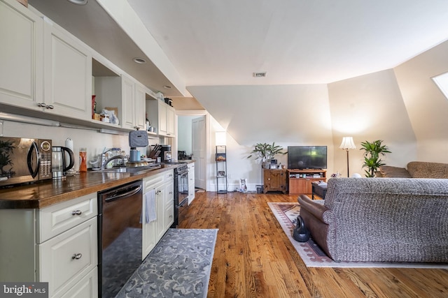 kitchen featuring black dishwasher, sink, hardwood / wood-style floors, and white cabinets