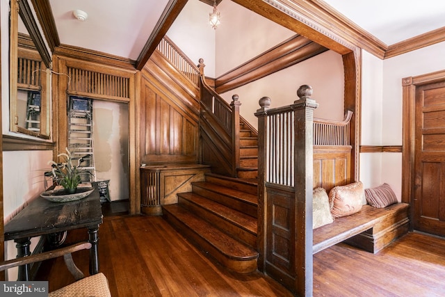 stairway with crown molding and wood-type flooring