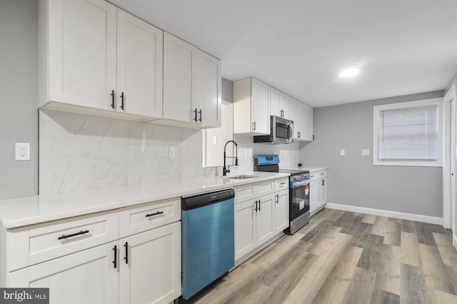 kitchen with white cabinets, tasteful backsplash, light hardwood / wood-style flooring, sink, and stainless steel appliances