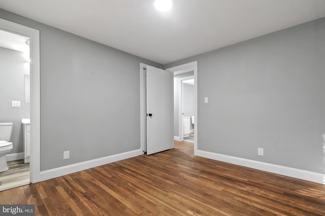 unfurnished bedroom with ensuite bath and dark hardwood / wood-style flooring