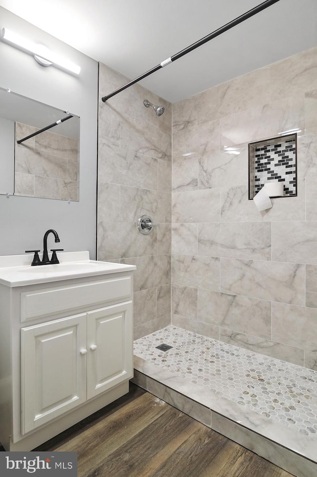 bathroom with vanity, a tile shower, and wood-type flooring