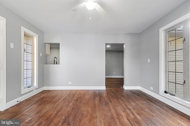 empty room with plenty of natural light, ceiling fan, and dark hardwood / wood-style flooring