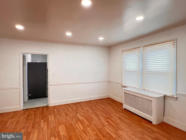 unfurnished room featuring light hardwood / wood-style floors, radiator, and crown molding