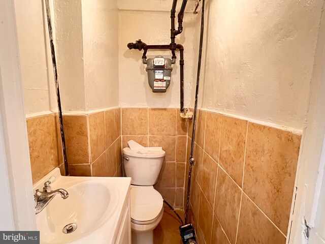 bathroom featuring vanity, toilet, and tile walls