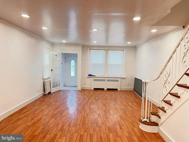 foyer with hardwood / wood-style floors, crown molding, and radiator