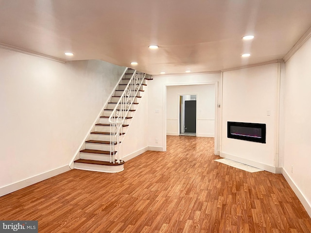 basement with light hardwood / wood-style floors and ornamental molding