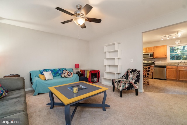 living room with rail lighting, ceiling fan, light carpet, and sink