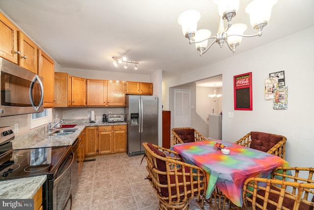 kitchen featuring stainless steel appliances, backsplash, sink, a notable chandelier, and pendant lighting