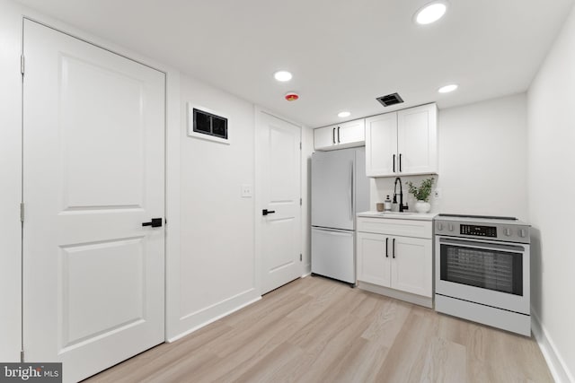 kitchen with white cabinets, electric range, light wood-type flooring, white fridge, and sink