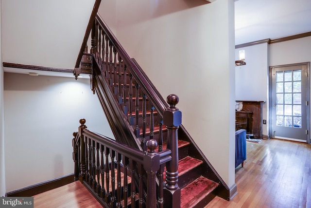 staircase with crown molding and hardwood / wood-style floors