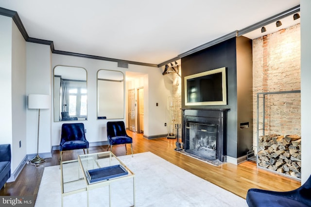 living room with crown molding, wood-type flooring, and a fireplace