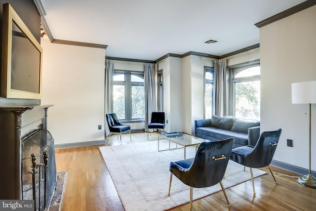 living room with ornamental molding, a brick fireplace, and light wood-type flooring