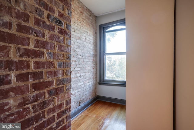 unfurnished room with brick wall and hardwood / wood-style flooring