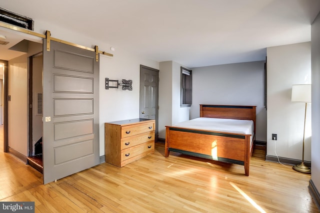 bedroom featuring light hardwood / wood-style flooring and a barn door