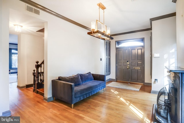 foyer with a notable chandelier, ornamental molding, and hardwood / wood-style flooring