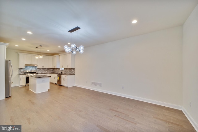 kitchen with white cabinets, hanging light fixtures, stainless steel appliances, light hardwood / wood-style floors, and a center island