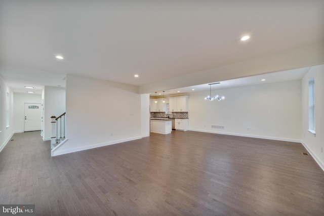 unfurnished living room featuring sink, hardwood / wood-style flooring, and an inviting chandelier