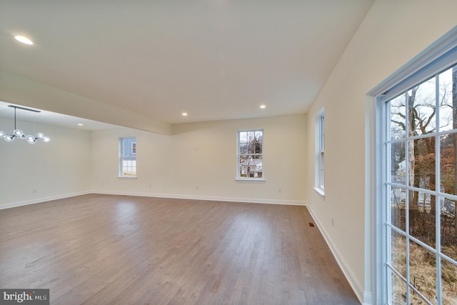 unfurnished room featuring a chandelier, wood-type flooring, and a wealth of natural light