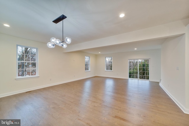 empty room with a notable chandelier and light hardwood / wood-style flooring