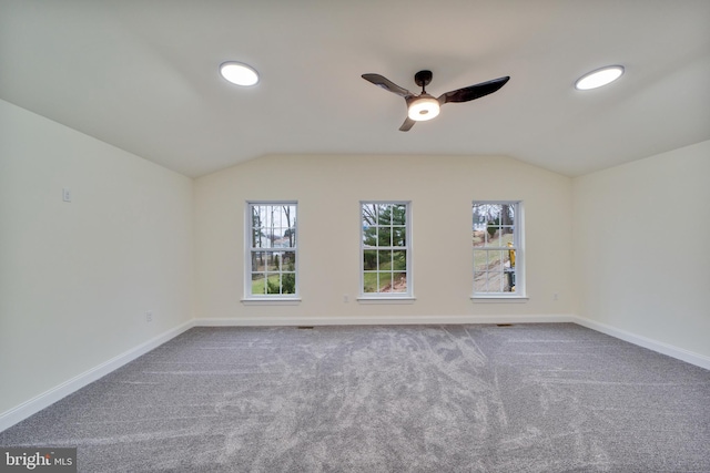 carpeted empty room featuring ceiling fan, lofted ceiling, and a wealth of natural light