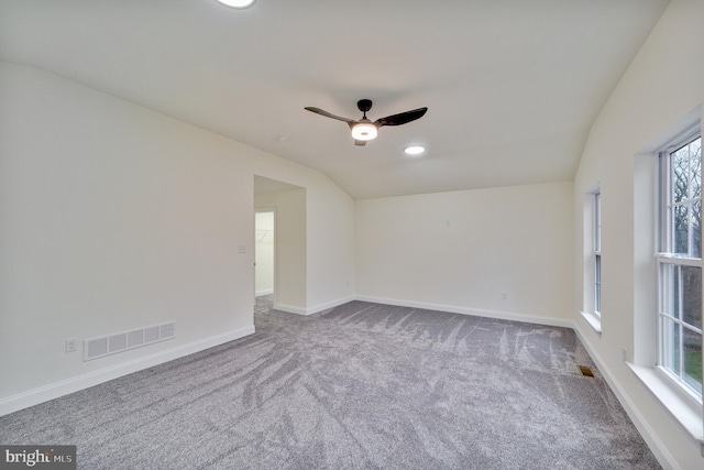 unfurnished room featuring vaulted ceiling, ceiling fan, carpet flooring, and plenty of natural light