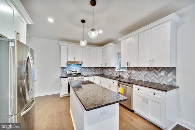 kitchen with appliances with stainless steel finishes, sink, a kitchen island, hanging light fixtures, and white cabinets