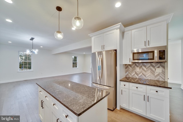 kitchen with white cabinetry, stainless steel appliances, light hardwood / wood-style flooring, and hanging light fixtures