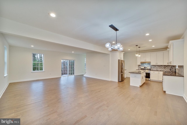 kitchen with light hardwood / wood-style flooring, hanging light fixtures, stainless steel appliances, a center island, and white cabinets