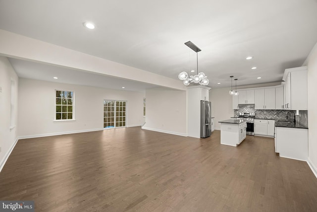 kitchen featuring stainless steel appliances, a center island, pendant lighting, white cabinetry, and dark hardwood / wood-style flooring