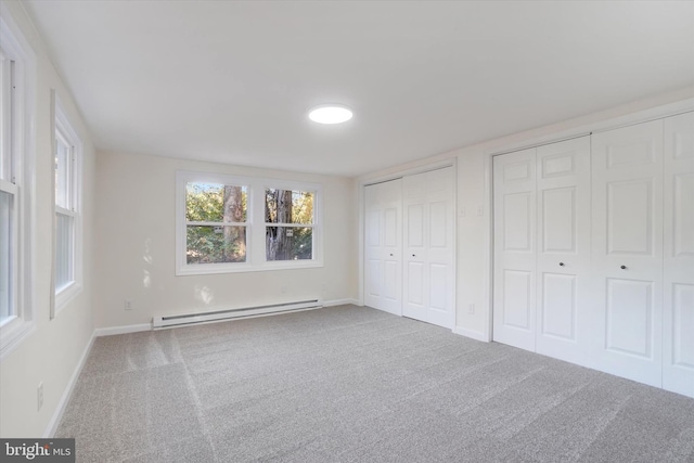 unfurnished bedroom with multiple closets, carpet floors, and baseboard heating