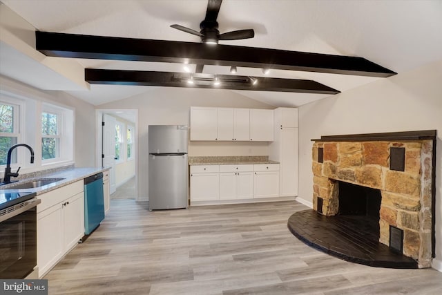 kitchen featuring sink, a stone fireplace, light hardwood / wood-style floors, stainless steel appliances, and white cabinets