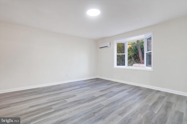 empty room with light wood-type flooring and a wall unit AC