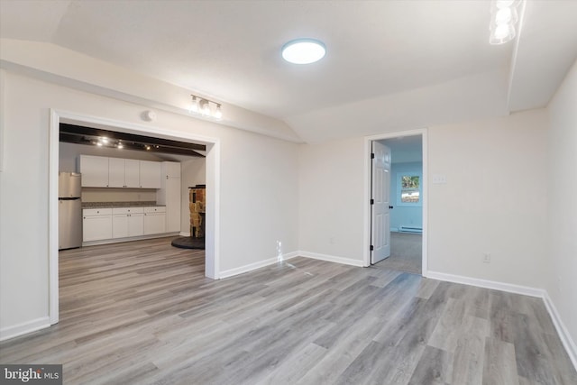 unfurnished living room featuring vaulted ceiling and light hardwood / wood-style floors