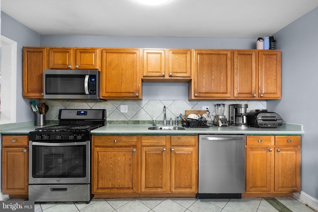 kitchen featuring decorative backsplash, sink, light tile patterned floors, and appliances with stainless steel finishes