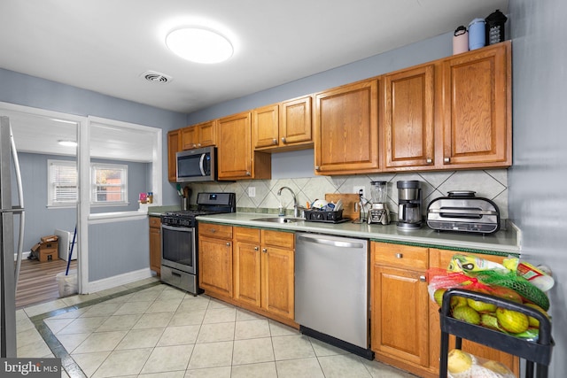 kitchen featuring backsplash, light tile patterned flooring, sink, and appliances with stainless steel finishes