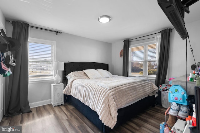 bedroom with multiple windows and dark wood-type flooring