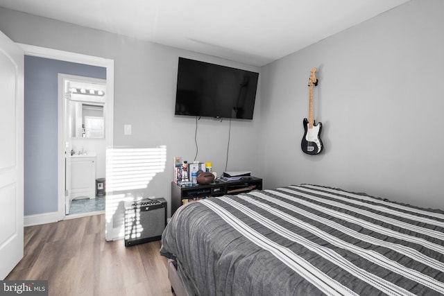 bedroom featuring connected bathroom and hardwood / wood-style flooring